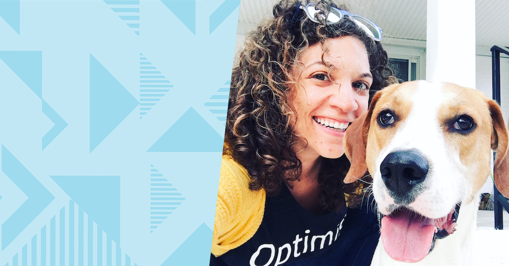 Elesha, a Capital One associate, poses next to a dog, next to a blue two-tone triangular background